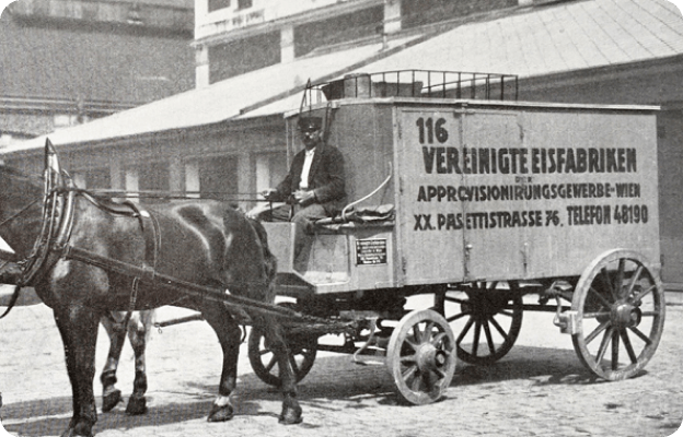 Historisches Foto einer Pferdetransportkutsche mit Aufschrift "Vereinigte Eisfabriken", auf dem Kutschbock sitzt ein Kutscher mit Zügel in der Hand.
