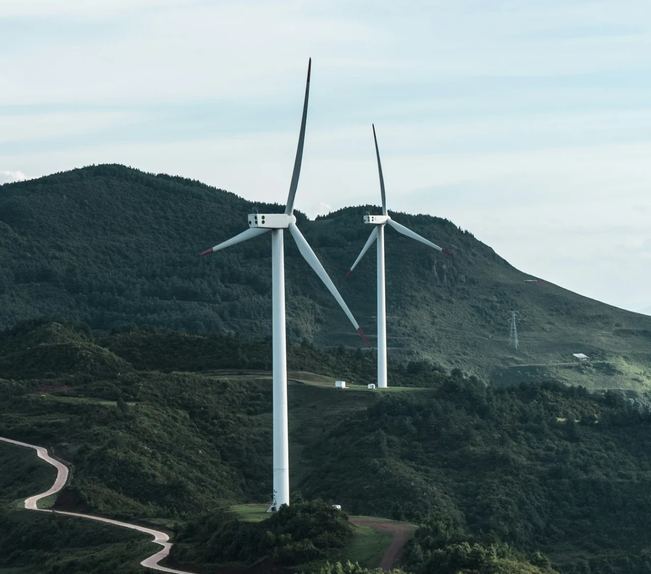 Zwei Windräder in einer Hügellandschaft