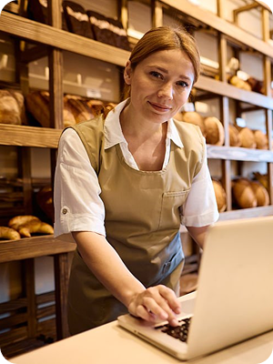Eine Mitarbeiterin in der Bäckerei vorm Regal mit Backwaren
