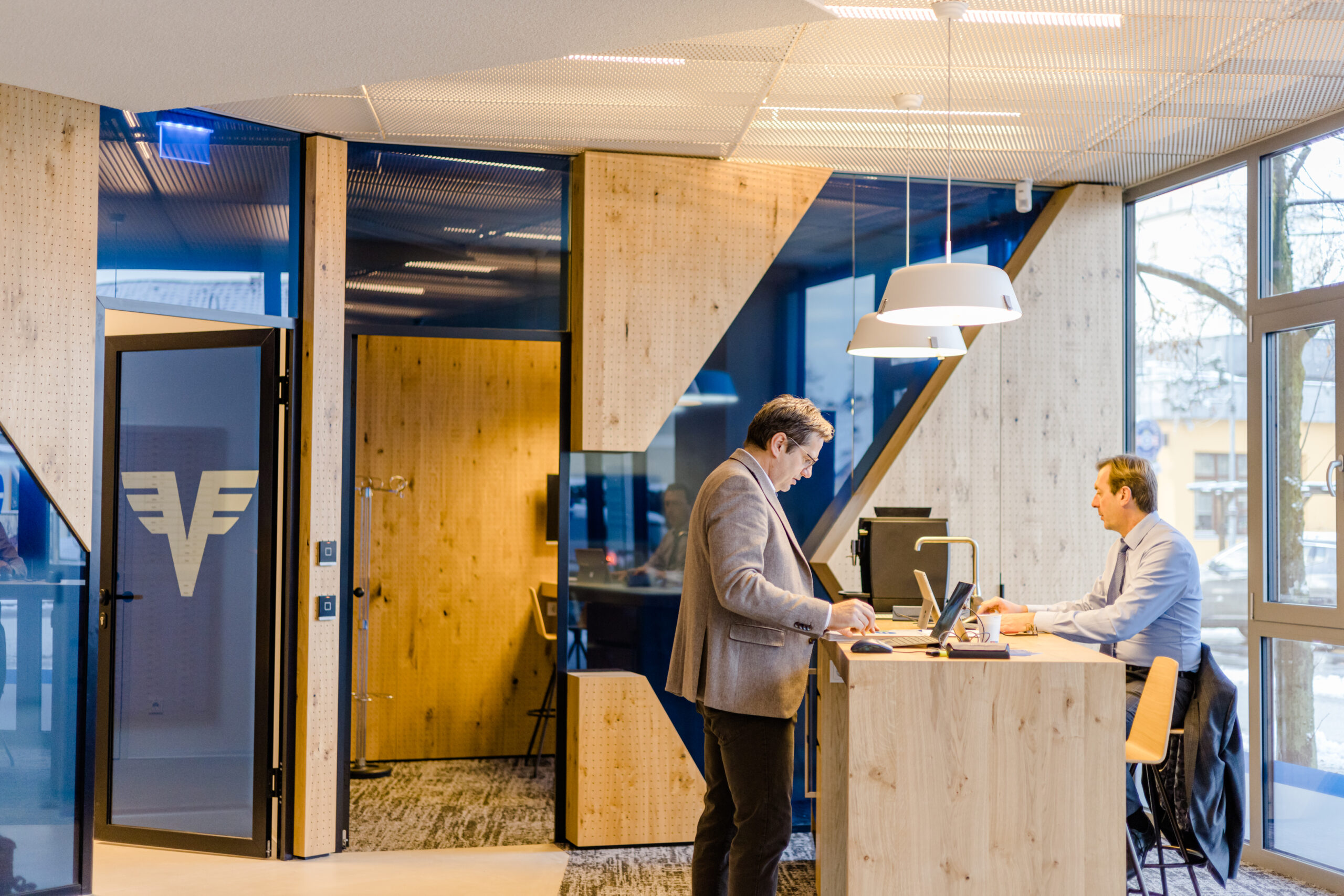 Blick in ein Büro der Volksbank - 2 Männder stehen an einem Arbeitstisch, helles, modernes Interieur.